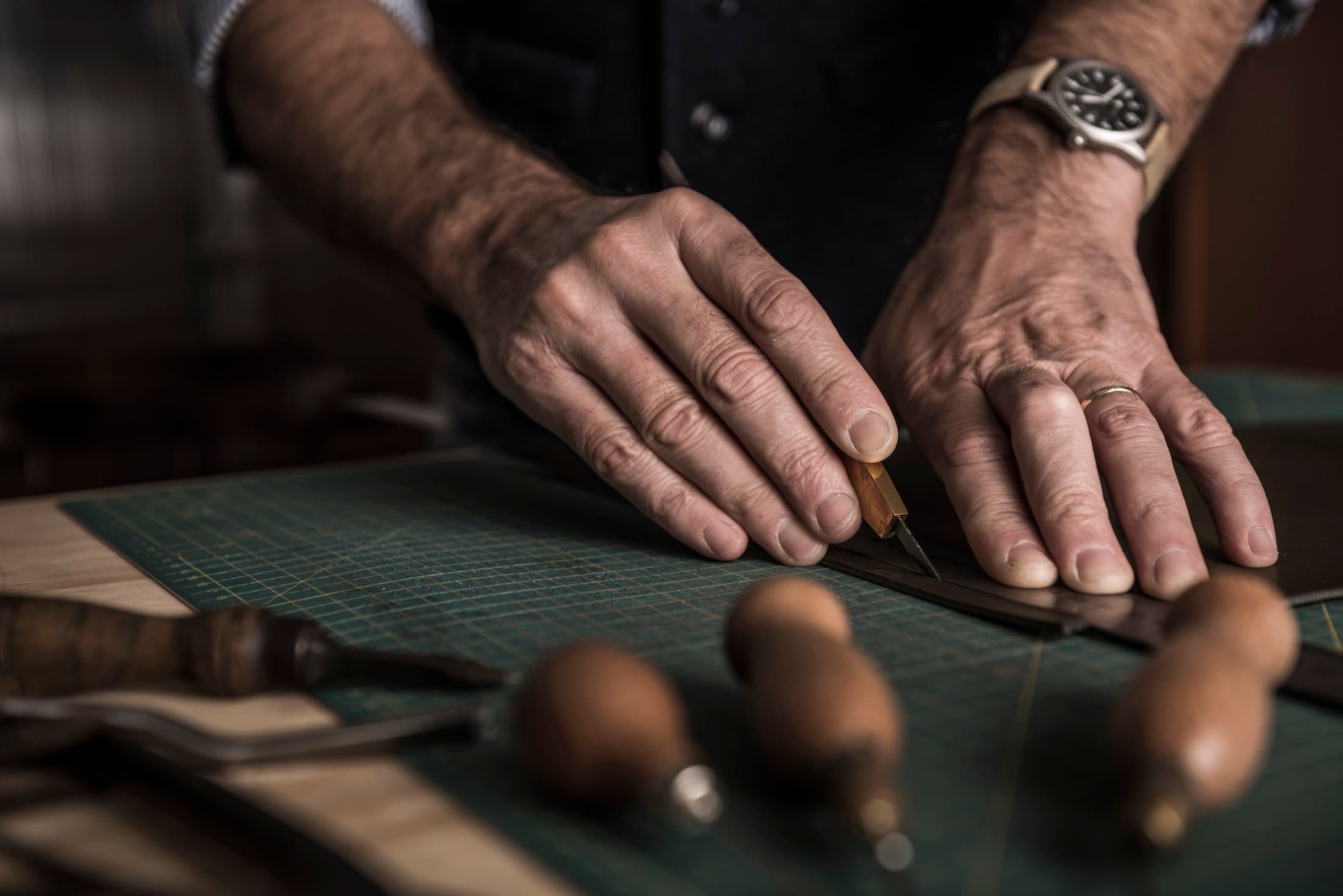 A leatherworker cutting leather by hand with traditional tools