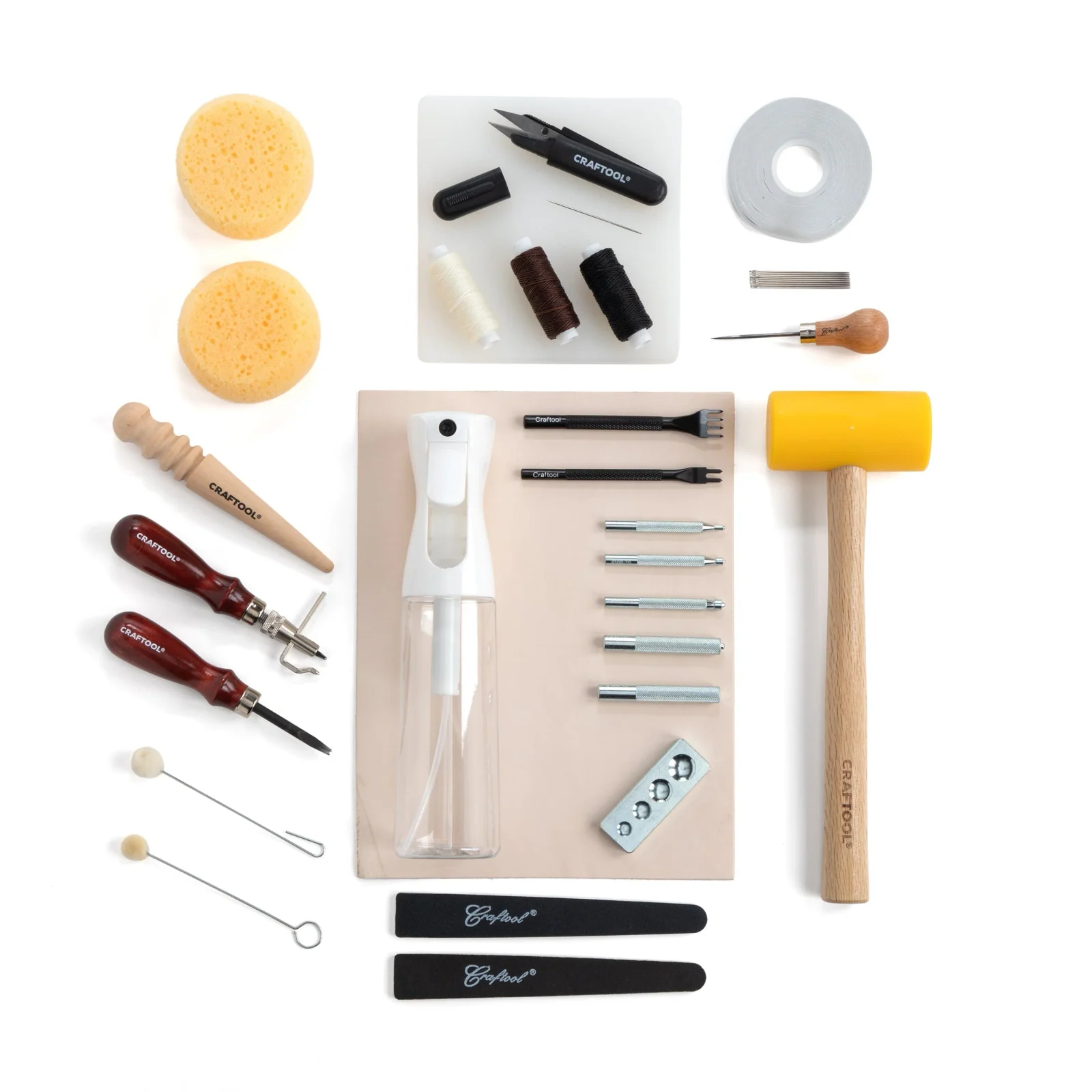 Leatherworking hand tools arranged on a white field