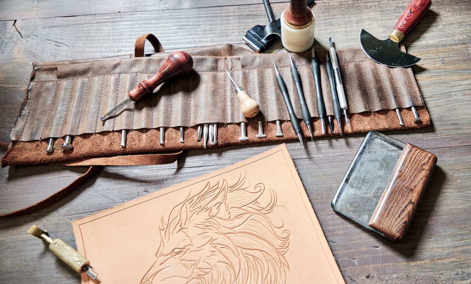 Leatherworking tools and a floral tooling pattern on a workbench