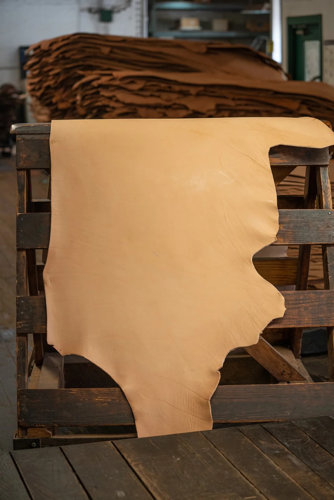 Natural Hermann Oak Strap and Tooling leather displayed on a wooden rack
