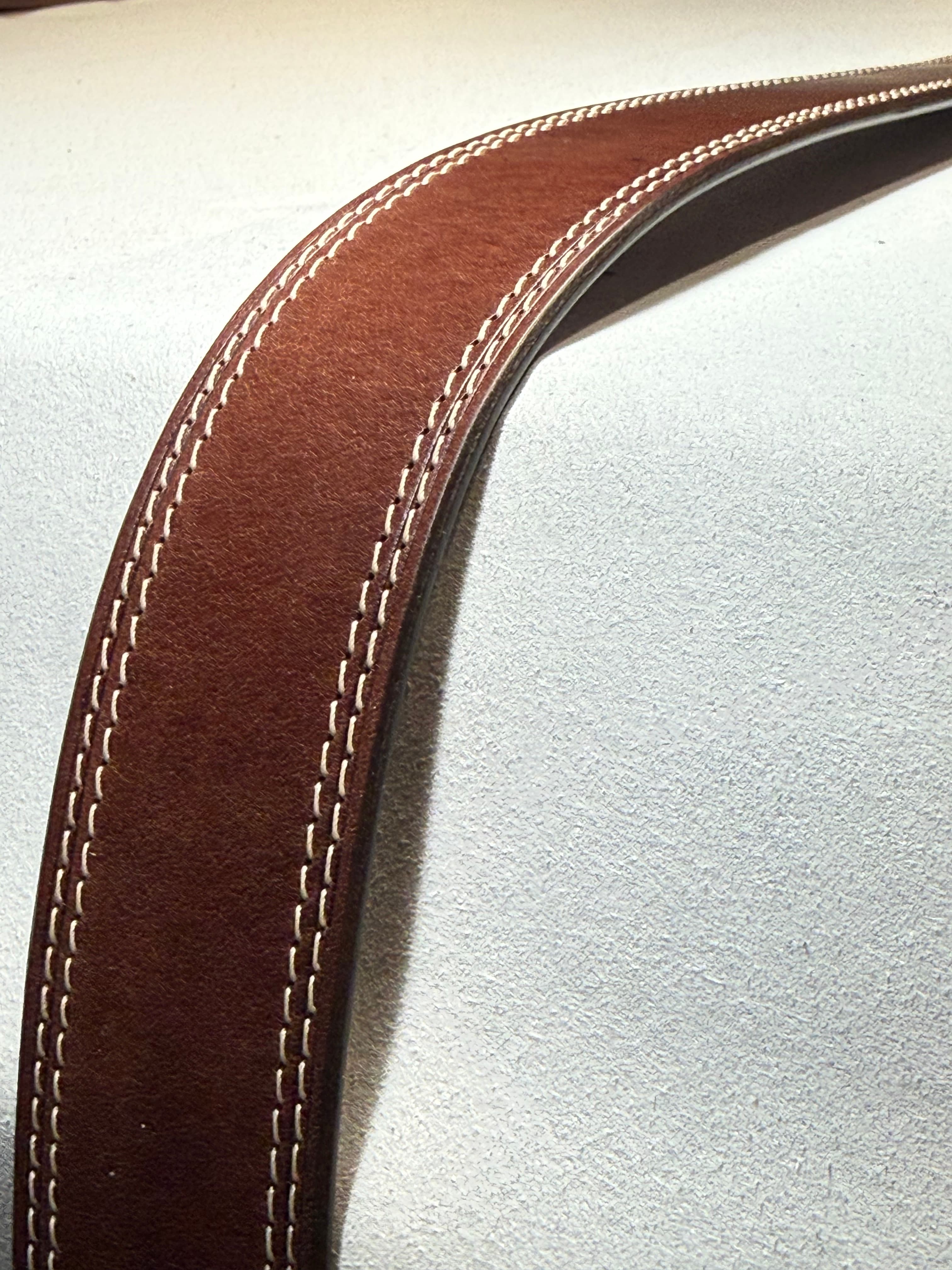 Close-up along a curved section of the belt, showing fine grain, paired stitch rows, and the finished dark edge.