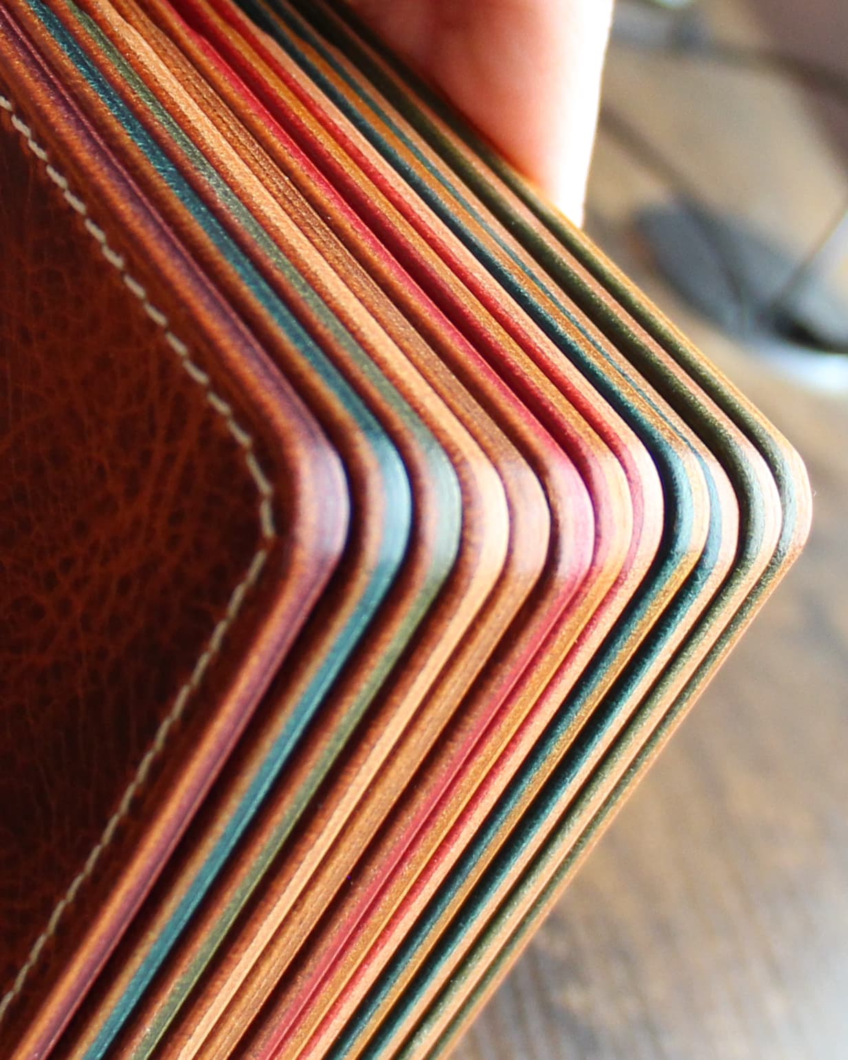 Close view of the multicolored finished edges of several leather wallets.